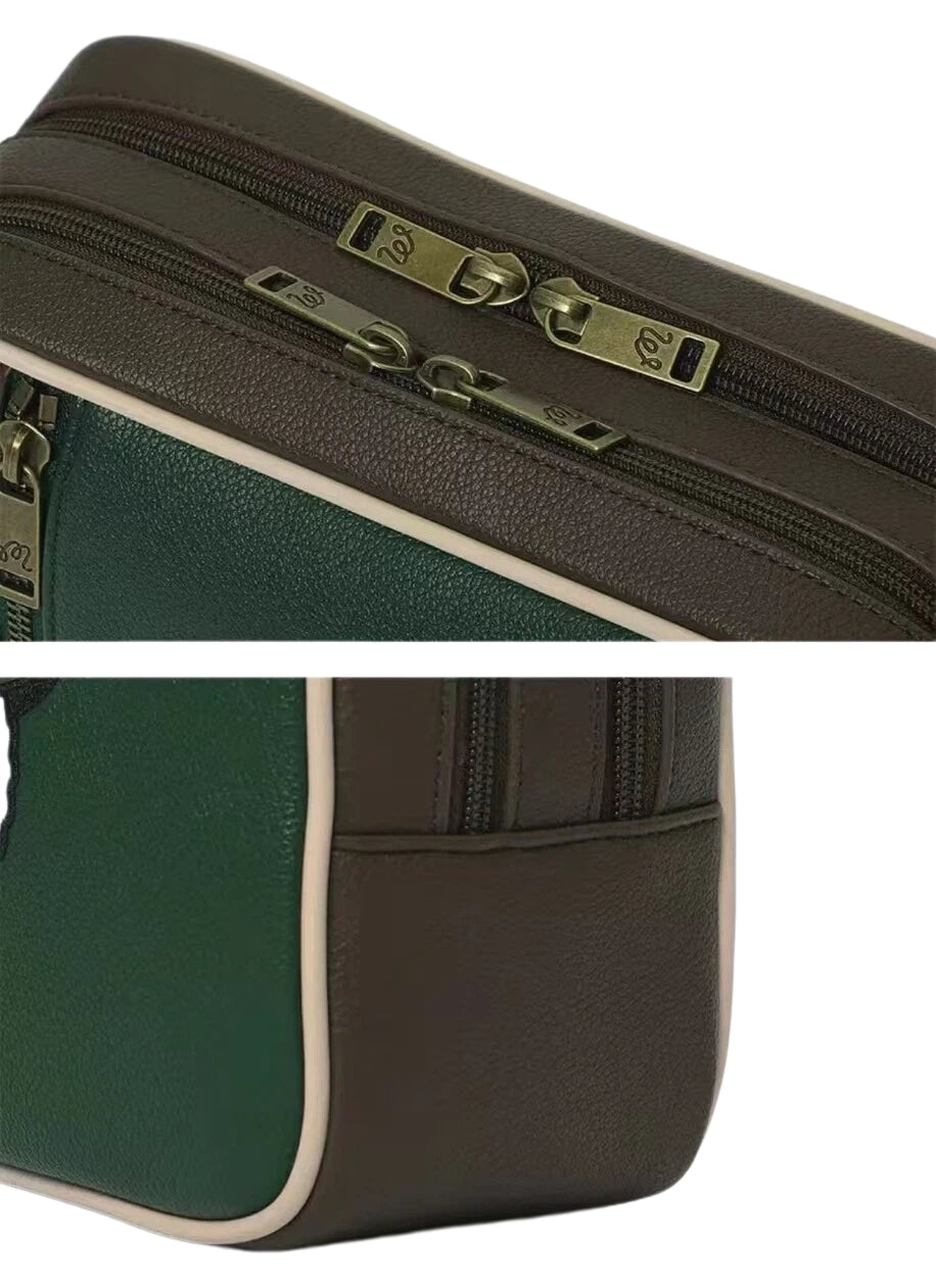 Close-up of the Malbon Golf clubhouse tote bag featuring dual zipper closure with antique brass hardware engraved with "M" logo. Premium leather-like texture and vintage-inspired design.

