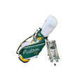 Malbon Golf Stand Bag in Green and White with the stand legs deployed, featuring the "Malbon Golf" script logo and a protective rain hood with a mascot graphic.