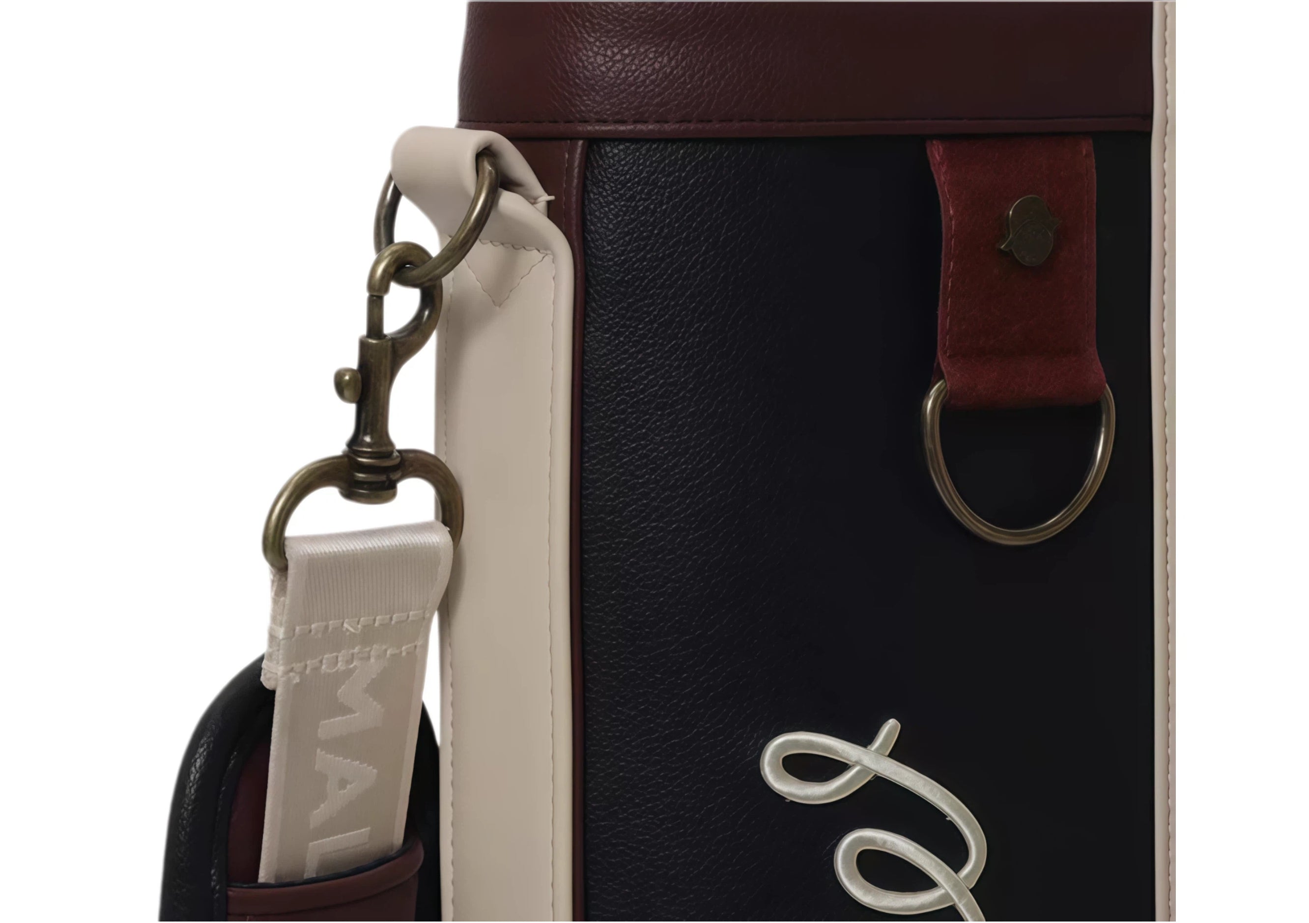 Top view of Malbon Golf Classic Sunday bag highlighting antique brass snap hook, leather-like loop, and branded zip puller. Premium craftsmanship and secure closure.