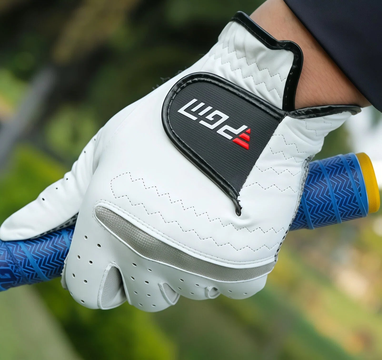 A close-up shot of a hand wearing a white PGM leather golf glove, gripping a golf club. The image highlights the high-quality stitching, the prominent PGM logo, and the comfortable, durable leather material.