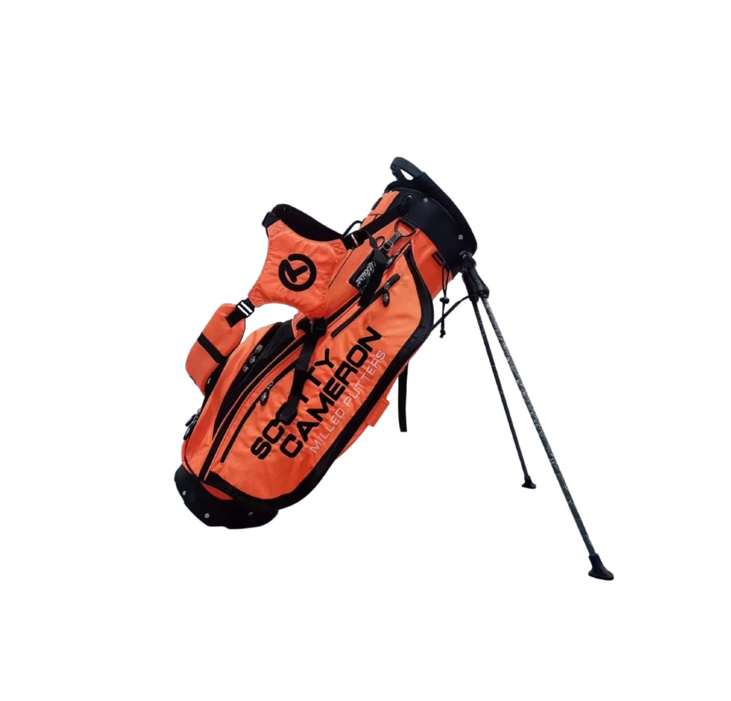 Side view of the Scotty Cameron Scottydog Stand Bag in Orange, showcasing the dual strap system, extended stand legs, and durable fabric construction with black detailing.