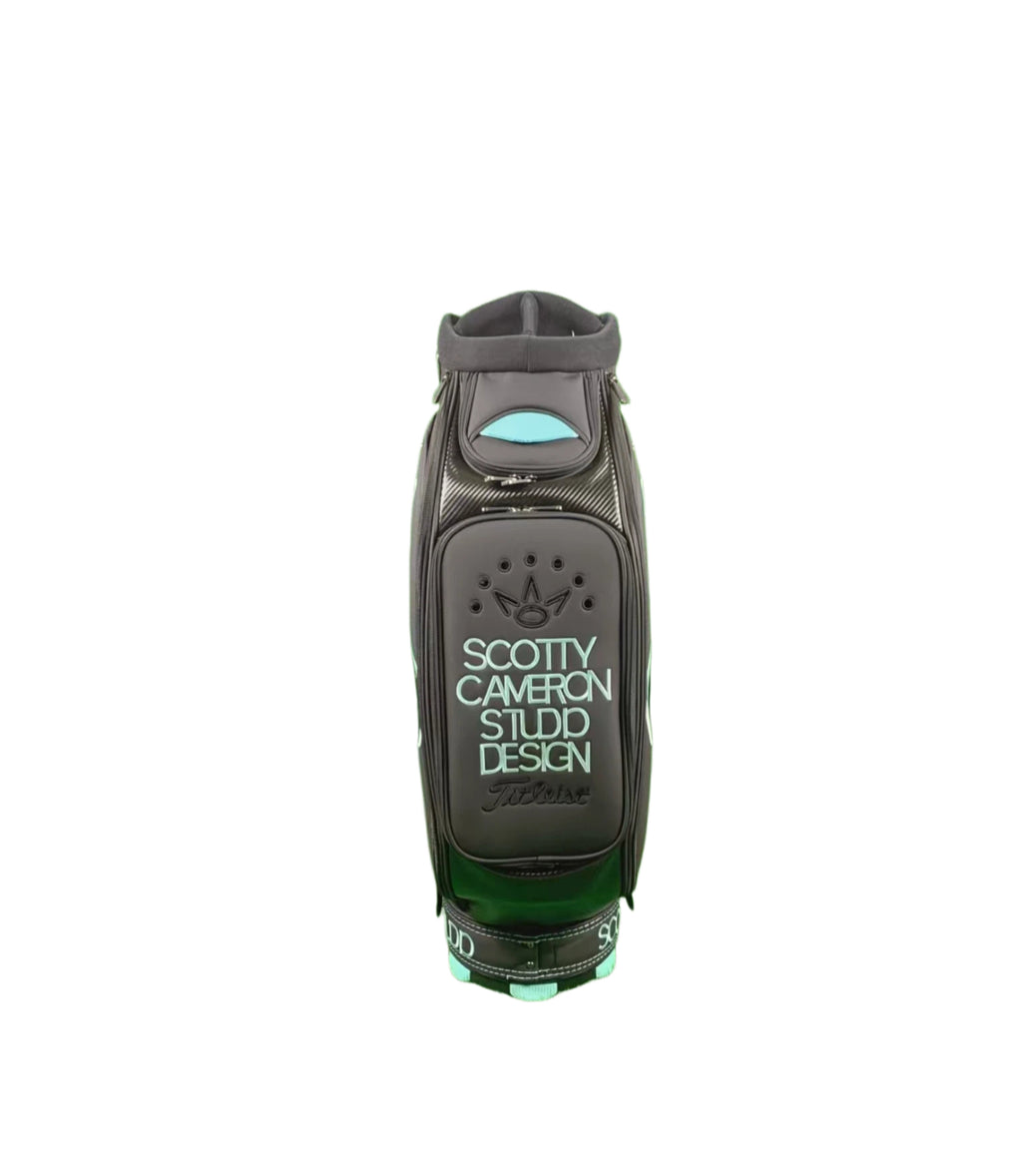  Front view of the Scotty Cameron Supercar Staff Bag, featuring a black body with light blue accents, the 'SCOTTY CAMERON STUDIO DESIGN' text, and a debossed crown logo on the main pocket.